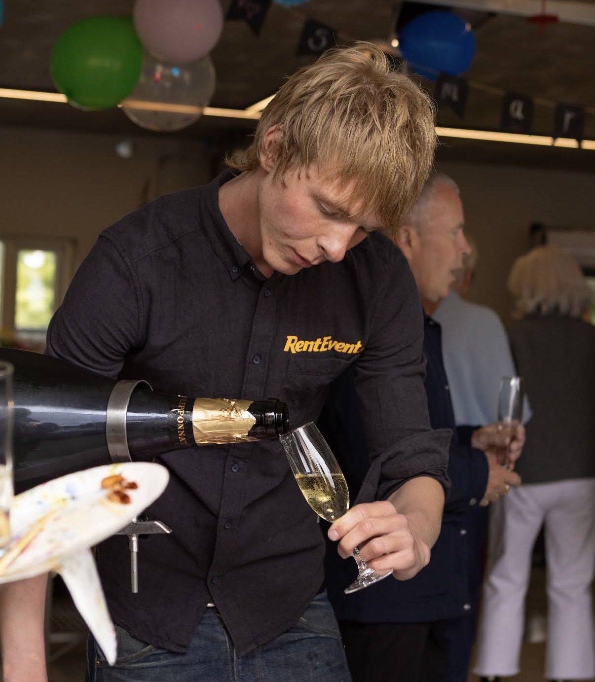 Barþjónn frá RentEvent hellir freyðivíni í glas í veislu